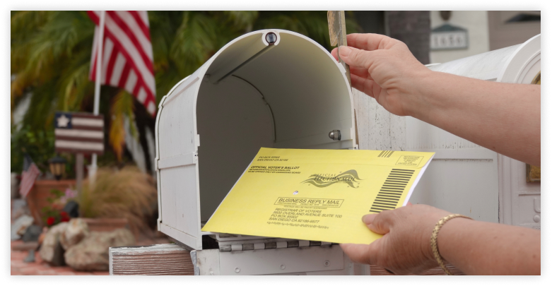 Mail in ballot placed in white mailbox with American flag in the background