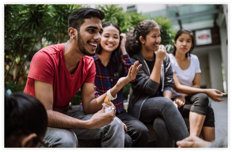 Young man speaking with group of young women, smiling and speaking with his hands